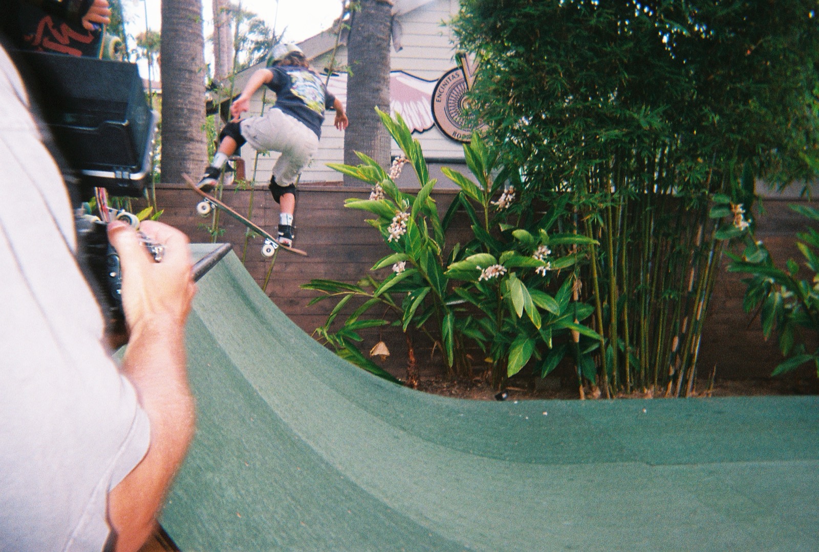 An operator filming a skater on a ramp from behind the camera.